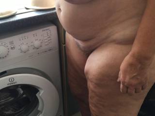 The washing machine emptied, now the naked lady waits for her clothes to dry