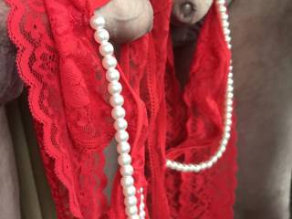 Mirrored photo of my hard smooth cock draped in my red lace crotchless panties with pearl string.
