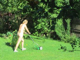 Nude women cut the grass in garden