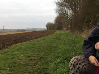 A large-breasted lady sits waiting for a friend in a beautiful location