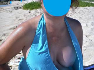 A sunny but breezy day at the beach.  My swimsuit blown open, exposing my left boob.