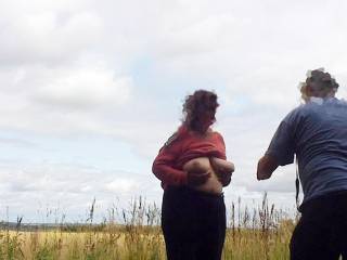 On a remote hilltop a lady holds her big tits up for a photographer