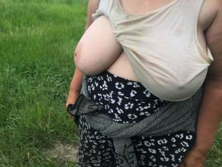 1 of 2 - from June 2021. Wearing a once-white loose-fitting top, my friend stands in countryside on top of a hill. One big tit out, one covered with a nipple poking through ;)
