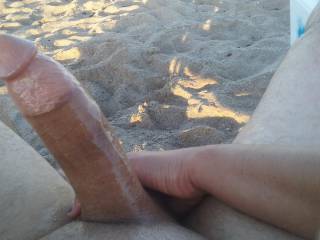 Playing with his oiled cock on the beach...