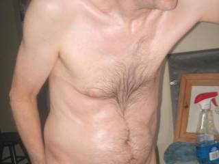 A partial body side/frontal as I stand near my bathroom sink as I use a bar mop towel on my mirror in April of 2025. A Powershot G6 camera was used.