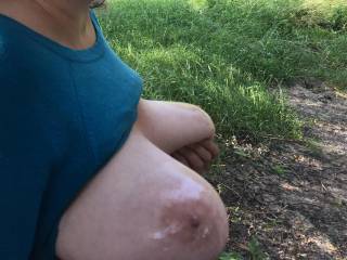 A sideways view, as my friend holds up her lovely tits after she put baby oil on them. We are in a dried up pond, with trees around it