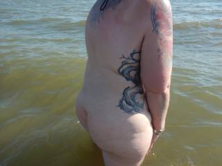 Mrs venturing in to the water on a nudist beach